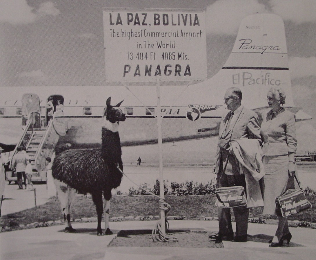 1959 Customers and a llama pose for a picture at the airport in LaPaz Bolivia with an aircraft of sister company Panagra in the background.